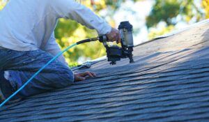 A residential roofer inspecting both a flat and a sloped roof section on a home during late autumn.